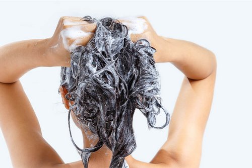 Eine Frau arbeitet Shampoo in die Haare ein.