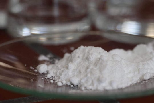 A small heap of caffeine powder has been put in a glass bowl.