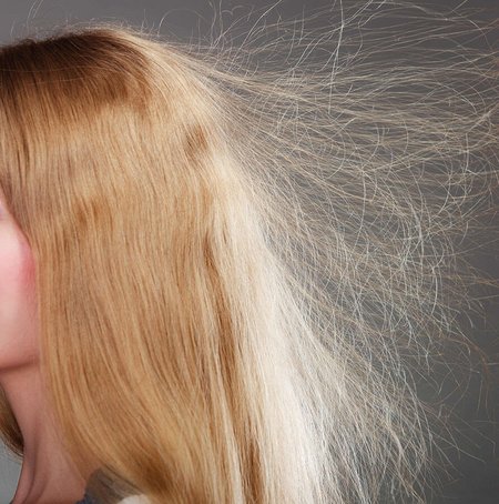 Eine Frau zeigt ihre fliegenden Haare. Sie sind elektrisch aufgeladen und stehen vom Kopf ab.